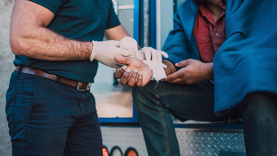 Paramedic wrapping a man's injured hand